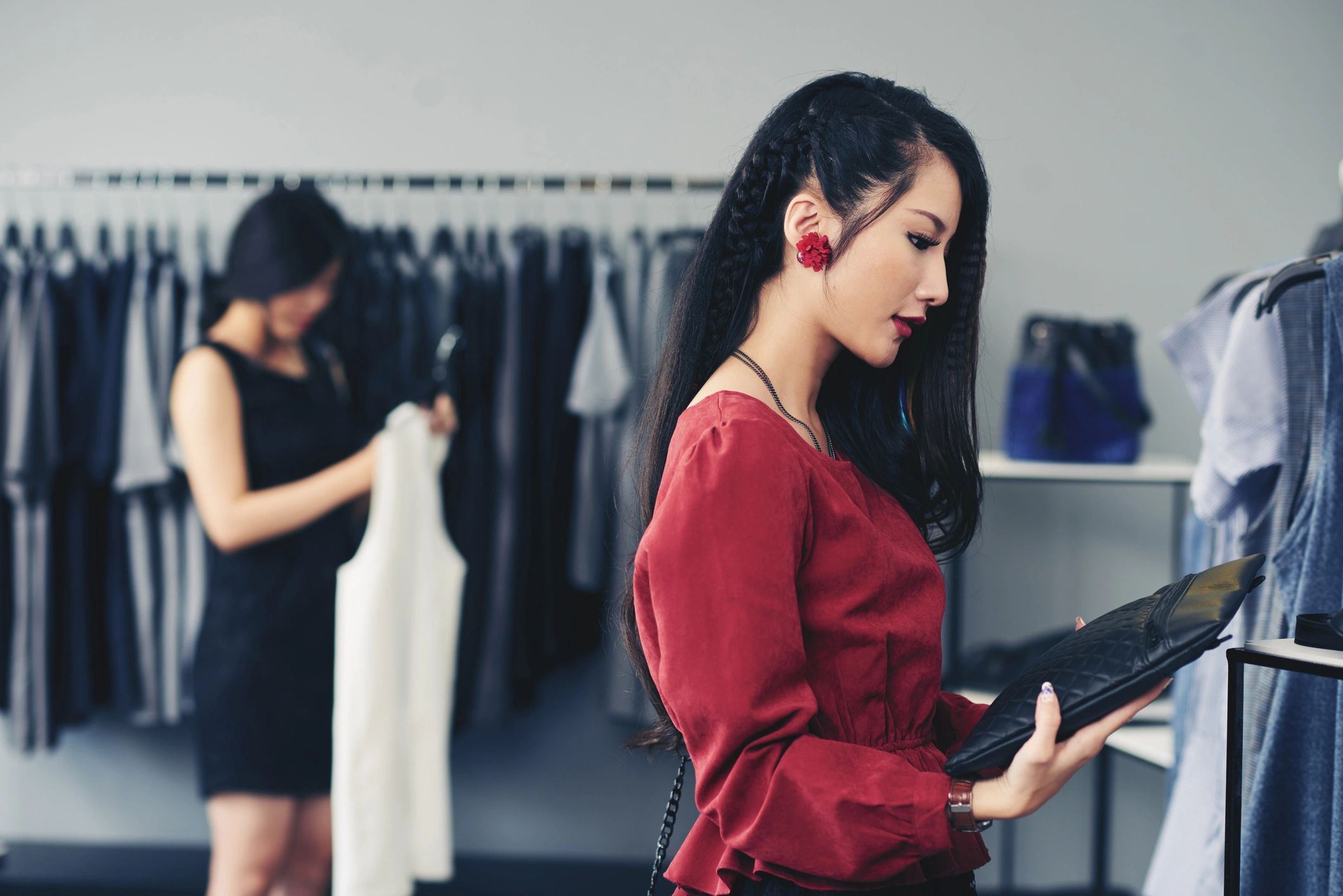 Young woman looking at black leather clutch in boutique