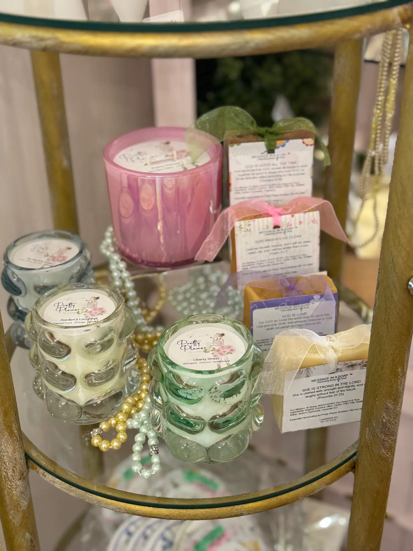 Decorative candles and soaps with inspirational labels displayed on a glass shelf.