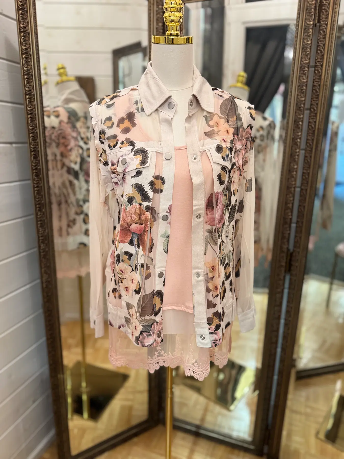 Floral and animal print jacket layered over a pink lace-trimmed top on a mannequin.